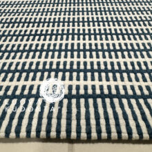 Turkoosi-valkoinen pikkumatto. Oikealla alhaalla yrityksen LuovaKudonta™ logo.